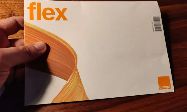 Dłoń trzyma kopertę z napisem "flex" i logo Orange. To oferta Orange Flex.