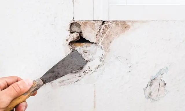 Mano con espátula preparando una pared para tapar agujeros.
