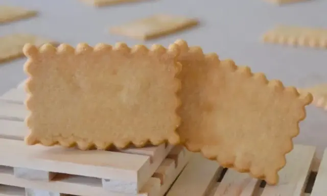 Deux biscuits rectangulaires aux bords festonnés, parfaits pour une recette biscuit personnalisé. Ils reposent sur des petites palettes en bois.