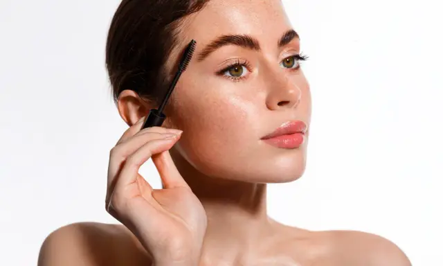 Une femme applique un sérum pour cils avec une brosse. Apprenez comment appliquer serum cils pour des cils plus longs et plus épais.