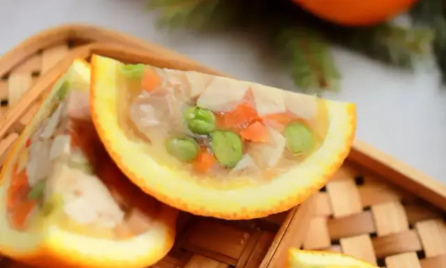 Galaretka z kurczaka z warzywami, podana w połówkach pomarańczy, wygląda apetycznie.
