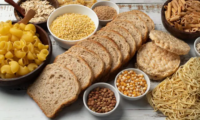 Stół pełen produktów, co ma dużo węglowodanów: makarony, płatki owsiane, chleb, ryż, kasza, kukurydza, soczewica.