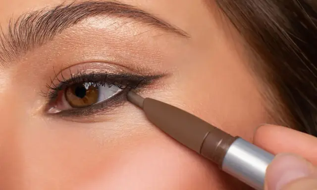 Ojo marrón con delineado invertido, aplicando lápiz marrón en la línea de agua inferior para un look dramático.