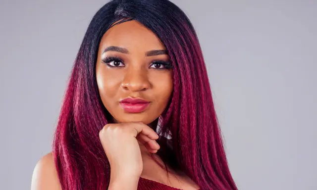 Una giovane donna con capelli color prugna, un look audace che le sta benissimo.