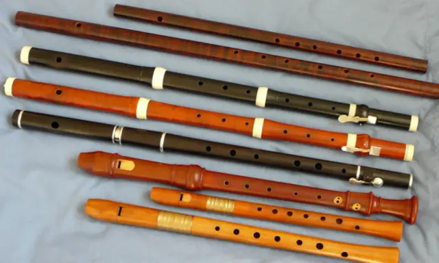 Różnorodne instrumenty renesansu, w tym flety proste o różnych rozmiarach i materiałach, ułożone na niebieskim tle.