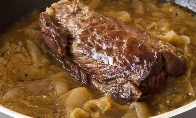 Une succulente buche d'onglet mijote dans une sauce aux oignons caramélisés, prête à être dégustée.