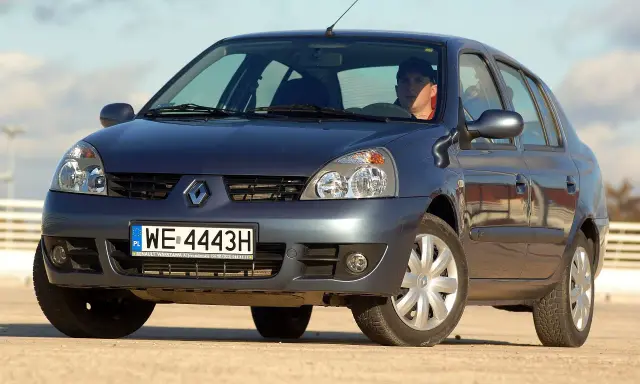 Ciemnogranatowy Renault Thalia 1.4 z kierowcą za kierownicą, zaparkowany na zewnątrz.