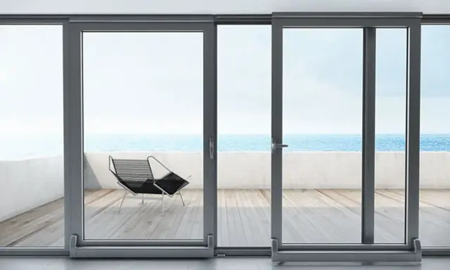 Ventanas osciloparalelas con vista al mar. Un sillón moderno en la terraza de madera.