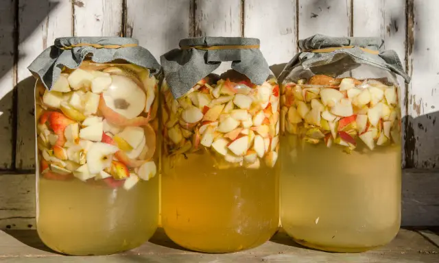 Trois bocaux remplis de pommes coupées, prêts pour la vinaigre de cidre recette de grand-mère.