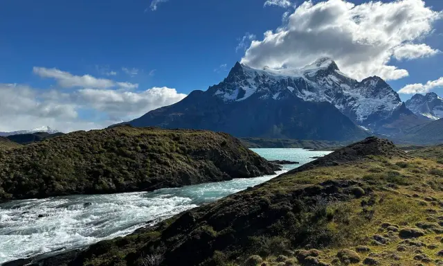 Wodospad w **Torres del Paine** z turkusową wodą i ośnieżonymi szczytami w tle.