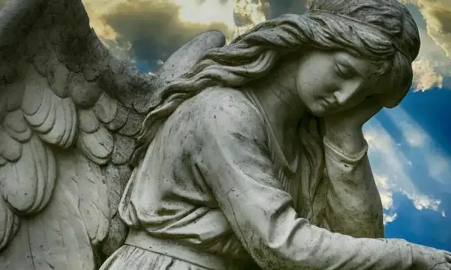Kamienna rzeźba anioła zamyślonego pod niebem. 1333 znaczenie tego widoku może być symbolem nadziei.