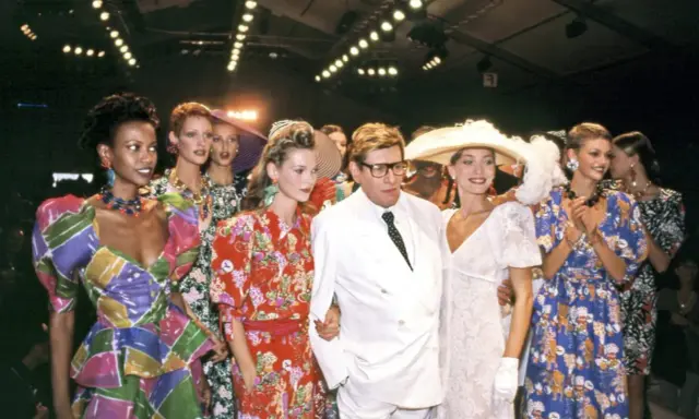 Models and designer Yves Saint Laurent at the Staley Wise Gallery fashion show, showcasing vibrant, patterned dresses and bold accessories.