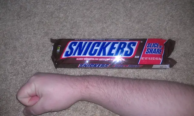 Opakowanie Snickers Slice 'n Share, obok ludzkiej ręki. Zastanawiasz się, snickers ile kalorii?