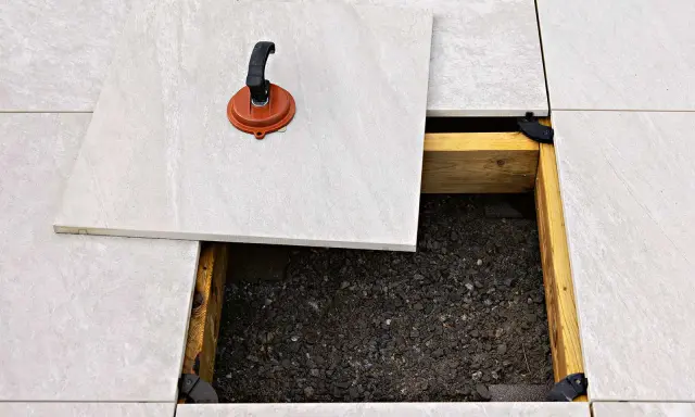 Lättskött klinker runt poolen läggs på en bärande konstruktion. En sugpropp används för att lyfta en platta.