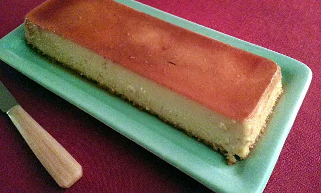 Un délicieux flan antillais, doré et onctueux, prêt à être dégusté sur une assiette verte.