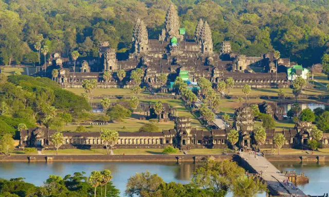 Majestatyczna świątynia Angkor Wat w Siem Reap, otoczona bujną zielenią, z mostem i jeziorem w tle.