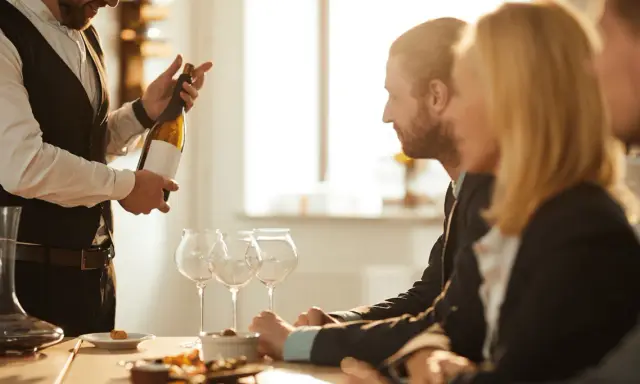 Ein Sommelier präsentiert eine Weinflasche. Die Bedeutung eines Sommeliers liegt in der Weinberatung und -auswahl.