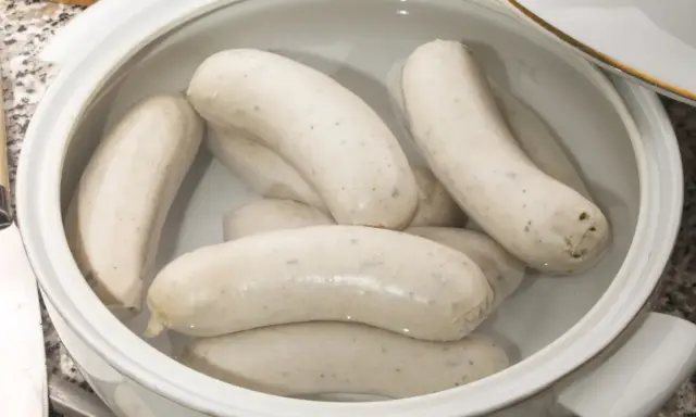 Biała kiełbasa w garnku z wodą, gotowa do parzenia. Idealny sposób, jak sparzyć białą kiełbasę, by była soczysta i smaczna.