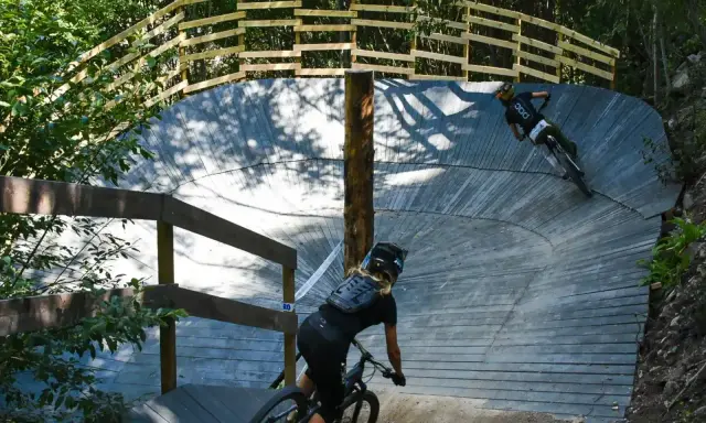 Två cyklister på en träbana i skogen, en spännande mtb-upplevelse nära Stockholm.