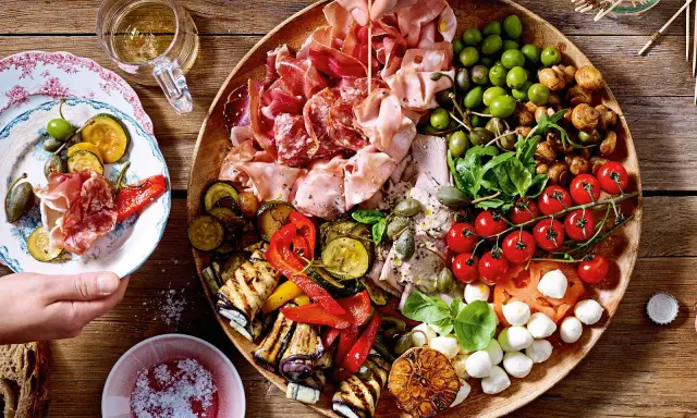 Große Platte mit Antipasti: Wurst, Schinken, Oliven, gegrilltes Gemüse, Tomaten, Mozzarella. Perfekt für Antipasti Rezepte.