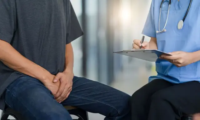 Mężczyzna w dżinsach i szarej koszulce rozmawia z lekarką, która notuje na kartce. Czy zapalenie prostaty przechodzi samo?