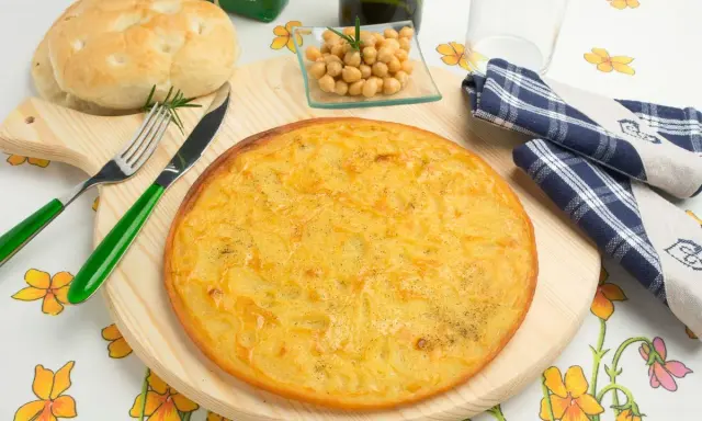 Una gustosa farinata di ceci in padella, pronta per essere gustata con pane fresco e un rametto di rosmarino.