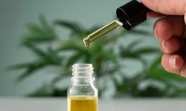 Une goutte d'huile essentielle tombe d'un compte-gouttes dans un flacon. Un remède naturel pour la toux grasse.