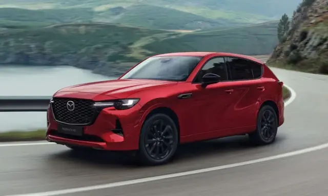 Czerwona Mazda CX-60 3.3 Diesel pokonuje zakręt na malowniczej drodze.