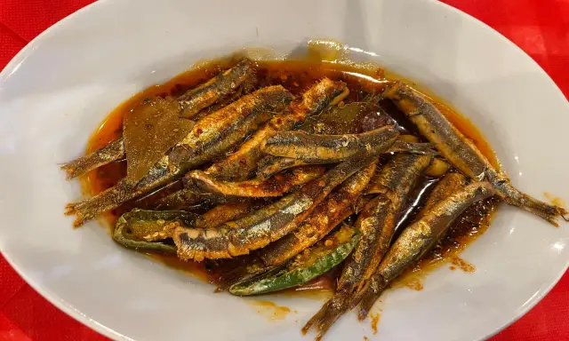Piatto di alici marinate, un classico dei piatti tipici calabresi pesce, condite con olio, peperoncino e aromi.