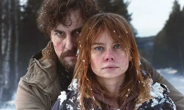 Två personer i snöig skog, en kvinna med rött hår och en man med mörkt lockigt hår. Scen från en svensk deckare serie.