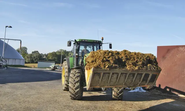Traktor mit vollem Ladebehälter, bereit für die Biogasanlage. Mais und Gülle werden verarbeitet.