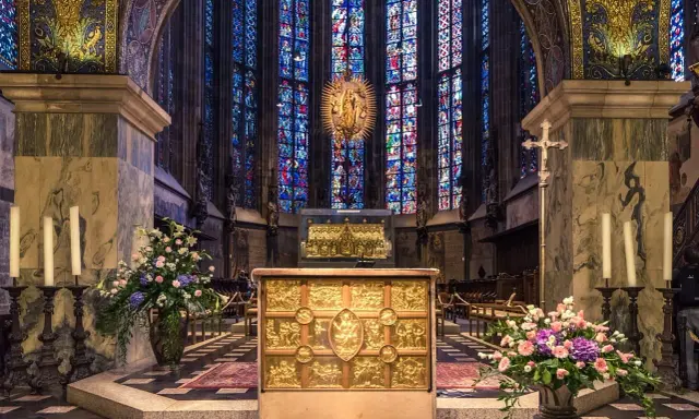Wnętrze katedry z ołtarzem i witrażami. Wzrok przyciąga złota szkatuła, przypominająca o treści psalmu 137.