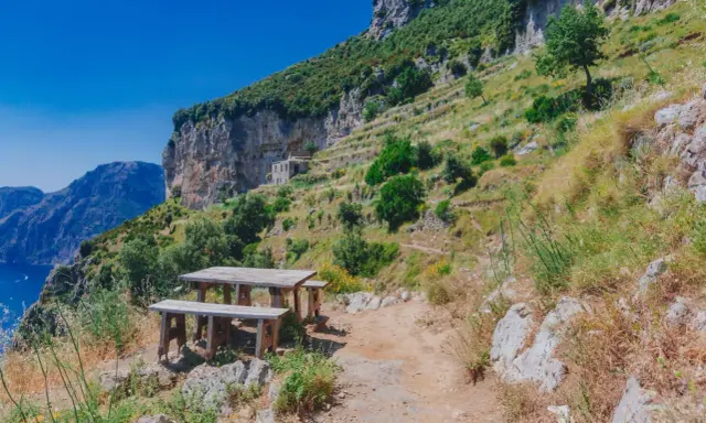 Un tavolo da picnic su un sentiero panoramico del Cammino degli Dei, Costiera Amalfitana. Vista mozzafiato sul mare e sulle montagne.