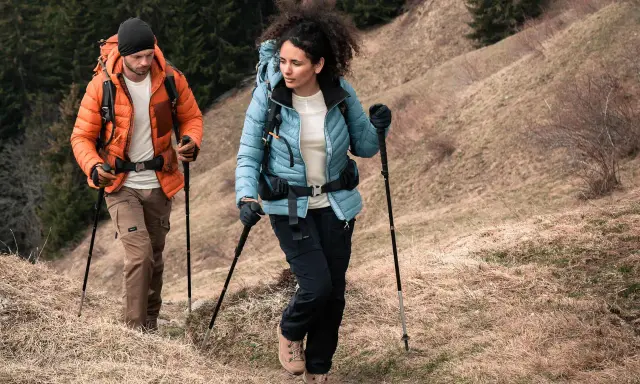 Para dobrać kije trekkingowe do wzrostu, zwróć uwagę na kąt 90 stopni w łokciu podczas marszu. Para turystów z kijkami na górskim szlaku.