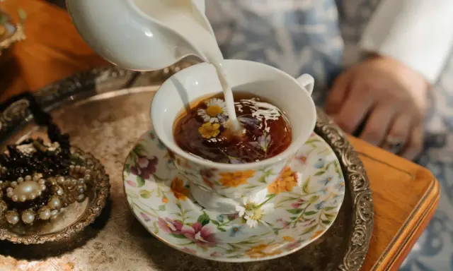 Té floral servido en una taza decorada, perfecto para celebrar los 20 años de casados. Un detalle de joyas antiguas añade elegancia.