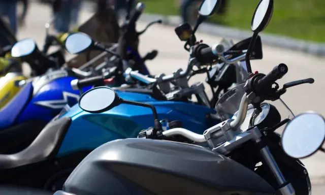 Manillar de moto con espejos y parte del depósito. Un carnet de moto a punto de ser usado.