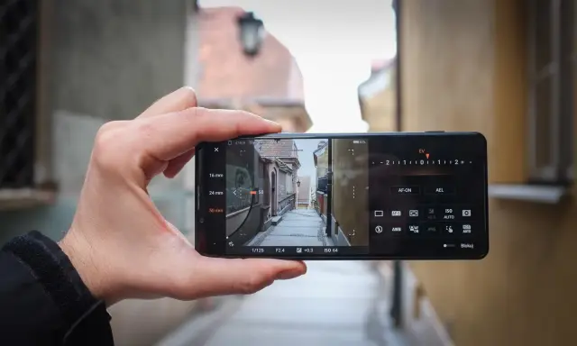 Dłoń trzyma smartfon Sony Xperia Pro i, kadrując wąską uliczkę. Widoczne ustawienia aparatu.