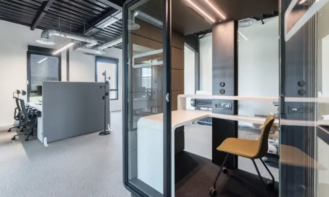 Un bureau moderne avec des cabines acoustiques et du mobilier flex office, idéal pour la concentration.