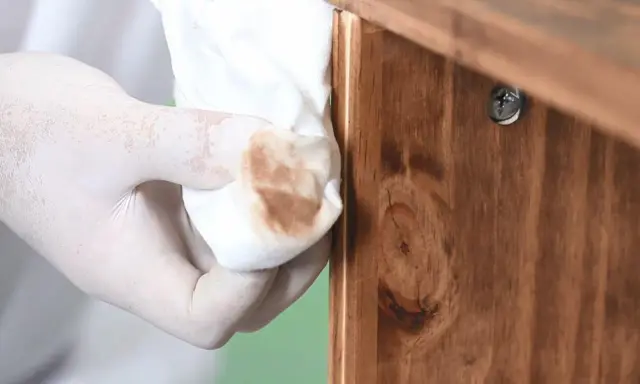 Guante de látex retirando barniz de un mueble de madera. Proceso para decapar un mueble lacado.
