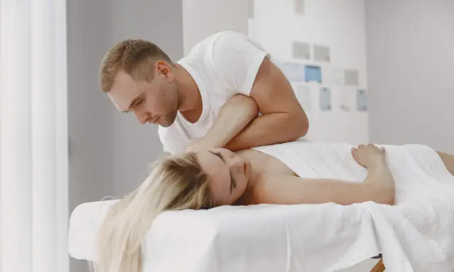 Fizjoterapeuta wykonuje neuromobilizację nerwu promieniowego u pacjentki leżącej na kozetce.