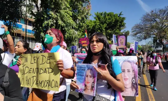 Protesters in El Salvador hold signs demanding identity rights and justice. One sign reads "Without identity law, there is no democracy.