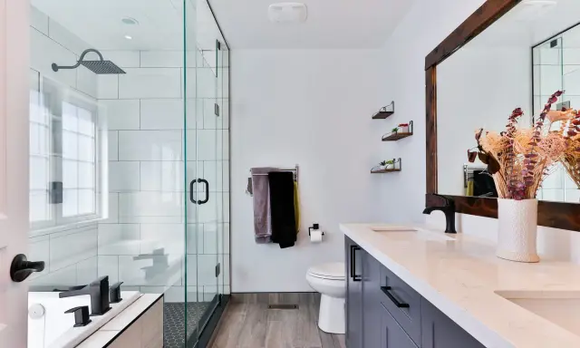Baño moderno con ducha de cristal, inodoro, lavabo doble y un gran espejo. Las ventanas para baños pequeños son clave para la luminosidad.