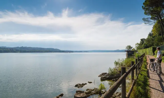 Ciclista ammira un lago in Lombardia, godendosi una delle tante ciclabili panoramiche.