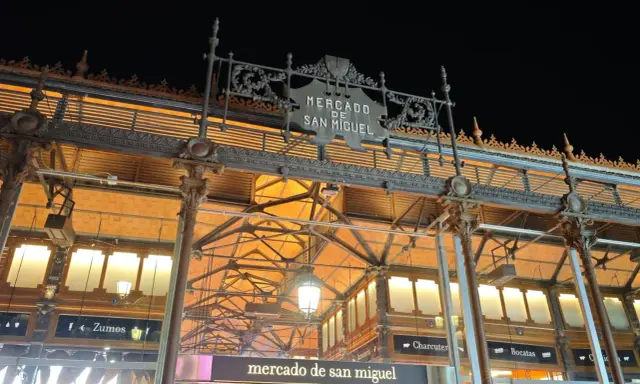 Das Mercado de San Miguel bei Nacht, mit seinem verzierten Eingang und den Lichtern, die durch das Glasdach scheinen.