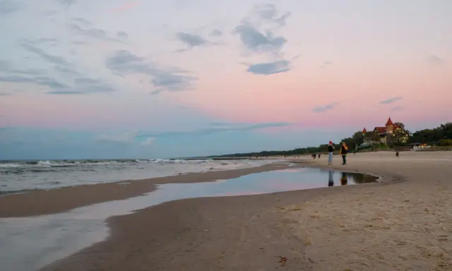Zachód słońca nad morzem w Łebie. Piękne łeba atrakcje, plaża, zamek i spacerujący ludzie.