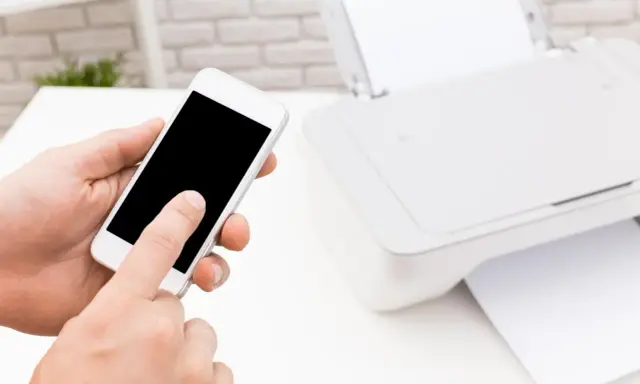 Instrukcja: jak połączyć telefon z drukarką. Smartfon w dłoni, obok drukarka z papierem.