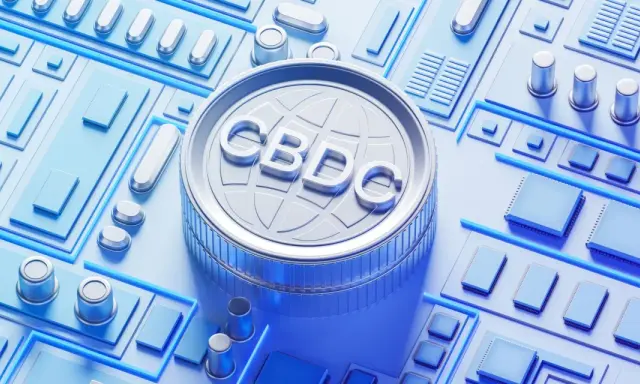 Moneta z napisem CBDC na tle obwodów drukowanych. Zastanawiasz się, cbdc co to? To cyfrowa waluta banku centralnego.