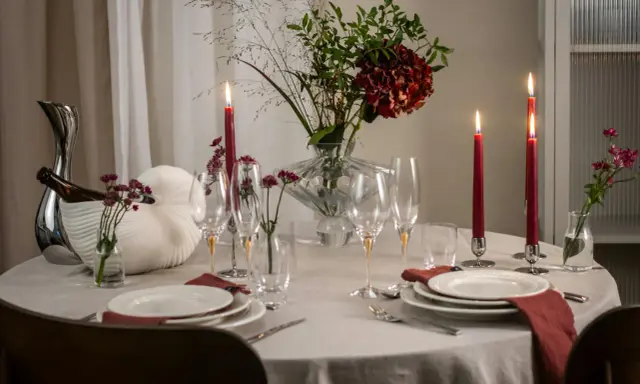 En vacker dukning med röda ljus, blommor och glas. En perfekt inramning för en mysig middag.