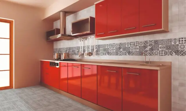 Cocina moderna con gabinetes rojos brillantes y una cenefa de azulejos con patrones geométricos en blanco y negro.