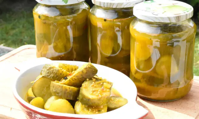 Słoiki z ogórkami z curry i miseczka z pokrojonymi ogórkami. Idealne na letnie przetwory.